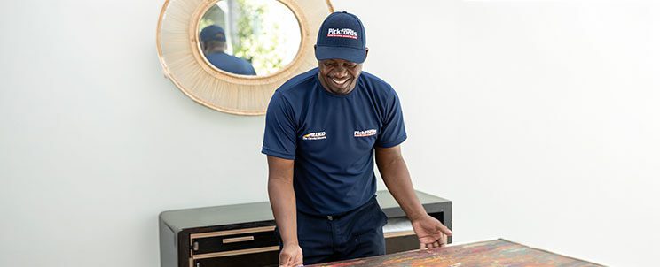 Specialist art mover packing a painting for safe relocation Professional art mover carefully packing a framed painting using protective materials to ensure safe transport during a local or international move.